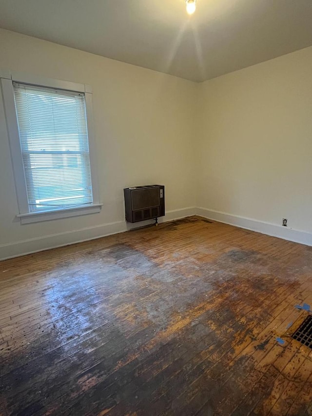 spare room with heating unit and dark hardwood / wood-style flooring