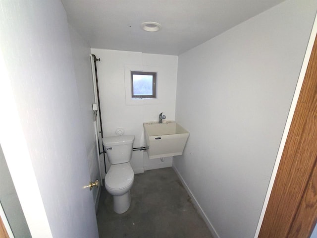 bathroom with concrete floors, toilet, and sink