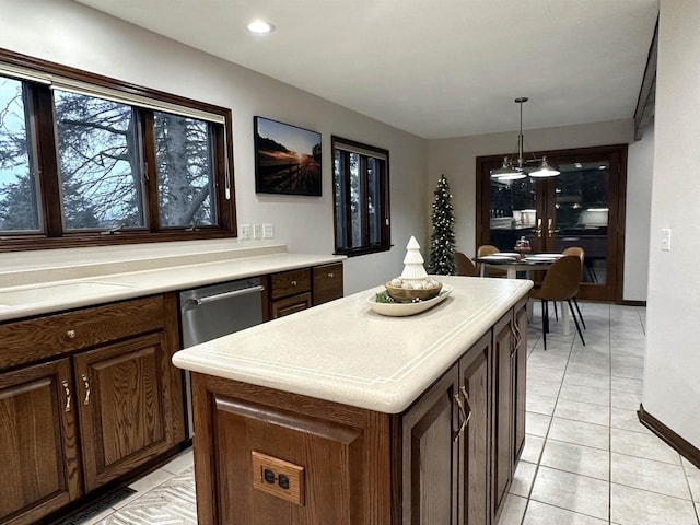 kitchen with dark brown cabinets, a kitchen island, hanging light fixtures, and light tile patterned flooring