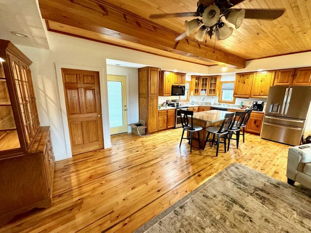 kitchen with wooden ceiling, appliances with stainless steel finishes, light hardwood / wood-style floors, and a kitchen breakfast bar