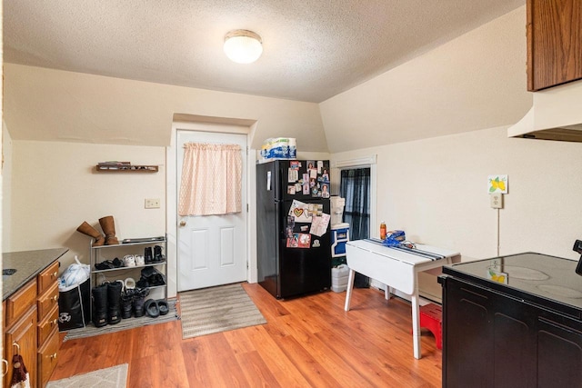 130 W Maple St, Viroqua, WI 54665 - kitchen featuring freestanding refrigerator, brown cabinetry, lofted ceiling, light wood-style flooring, and a textured ceiling