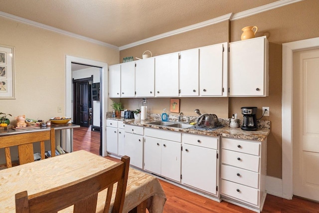 130 W Maple St, Viroqua, WI 54665 - kitchen featuring a sink, crown molding, wood finished floors, white cabinets, and light countertops