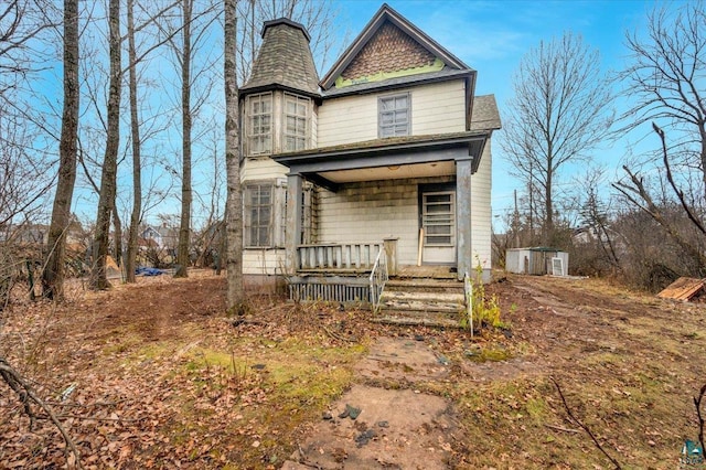 victorian home featuring a porch and a storage shed