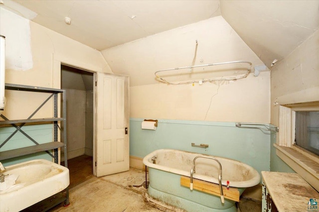 bathroom featuring a bathtub, concrete flooring, and lofted ceiling