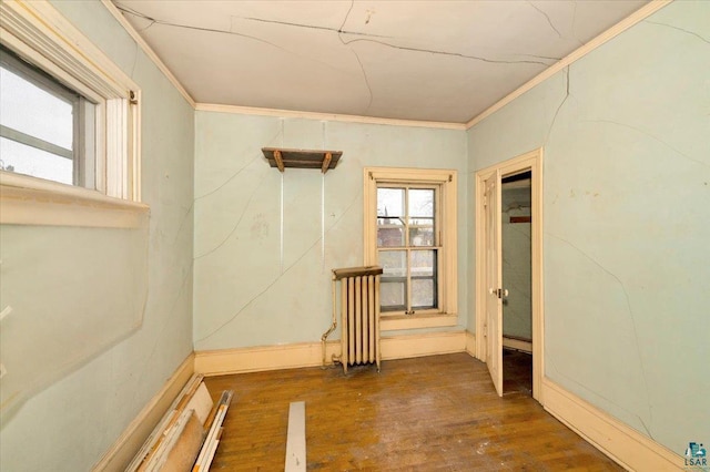 unfurnished room with dark hardwood / wood-style floors, crown molding, and radiator