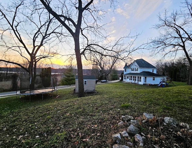 yard at dusk featuring a trampoline