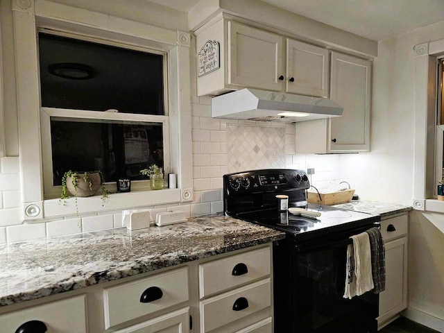 kitchen featuring decorative backsplash, black electric range oven, and light stone counters