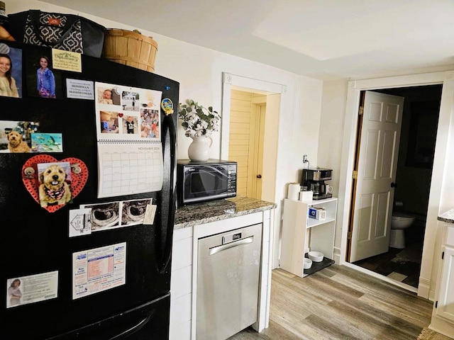 kitchen with light wood-type flooring, stone countertops, white cabinetry, and black appliances