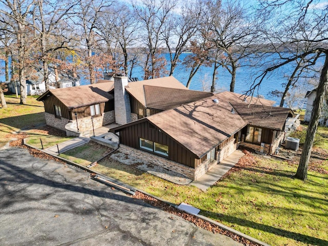 2572 N Shore Dr, Delavan, WI 53115 - view of side of home with board and batten siding, central air condition unit, a shingled roof, a chimney, and a yard
