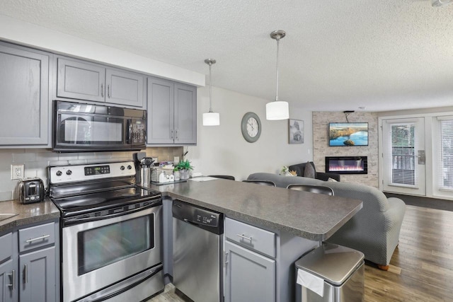 1093 Canyon Rd Unit 406, Wisconsin Dells, WI 53965 - kitchen with stainless steel appliances, a peninsula, gray cabinets, open floor plan, and a textured ceiling