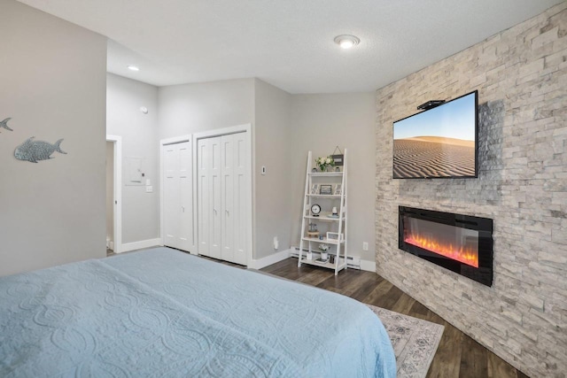 bedroom with vaulted ceiling, multiple closets, dark wood-type flooring, and a fireplace