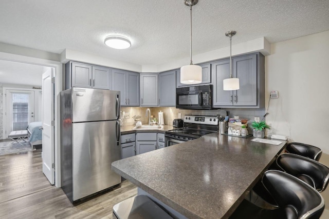 kitchen with kitchen peninsula, appliances with stainless steel finishes, hanging light fixtures, and a breakfast bar area