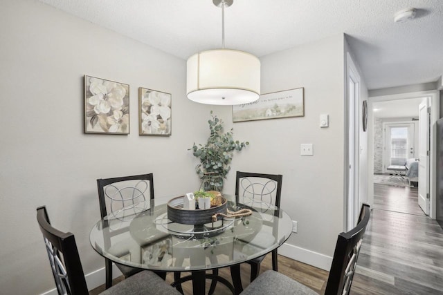 dining space with a textured ceiling and hardwood / wood-style floors