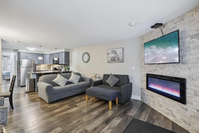 living room featuring a textured ceiling, a stone fireplace, and dark hardwood / wood-style floors