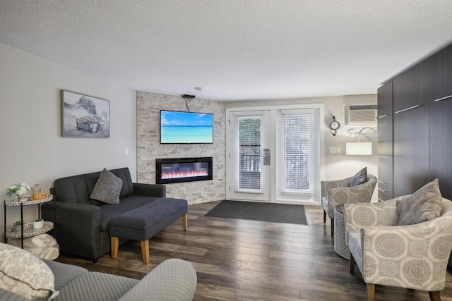 living room with a large fireplace, a wall mounted AC, a textured ceiling, and dark hardwood / wood-style flooring