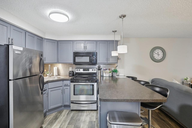 kitchen featuring a breakfast bar, decorative light fixtures, stainless steel appliances, dark wood-type flooring, and decorative backsplash