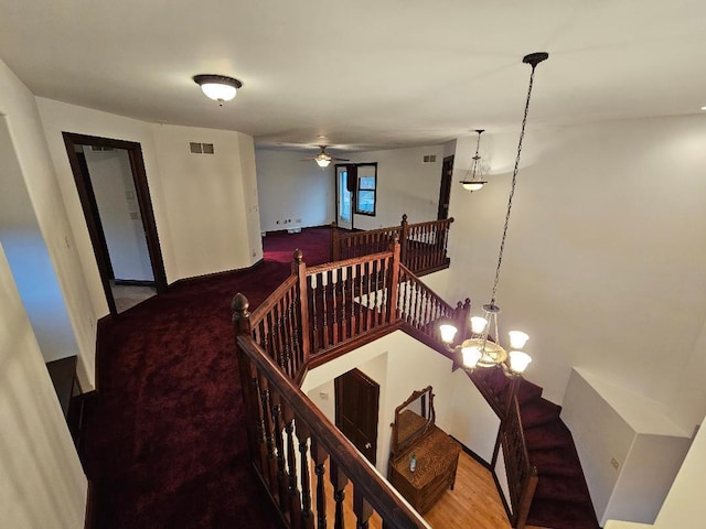 staircase with hardwood / wood-style floors and ceiling fan with notable chandelier