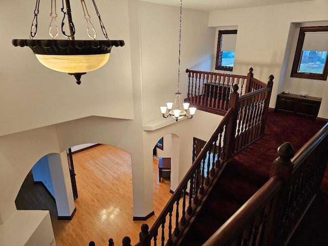 staircase with a notable chandelier and wood-type flooring