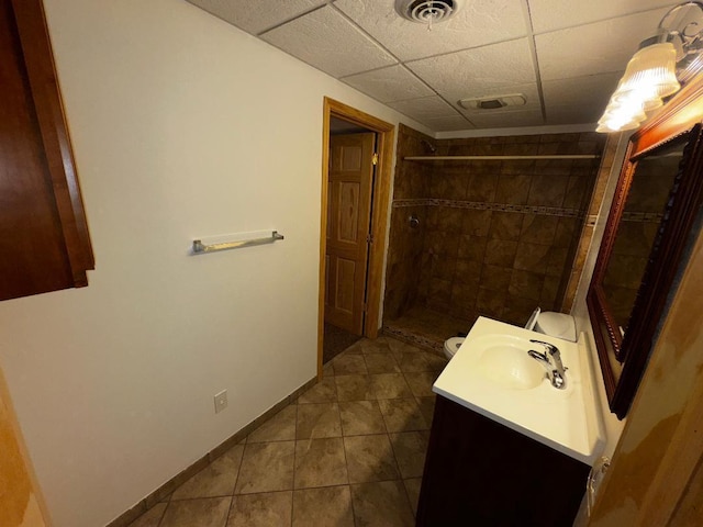 bathroom with tile patterned floors, a drop ceiling, vanity, a shower, and toilet