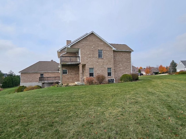 rear view of house with a balcony and a lawn