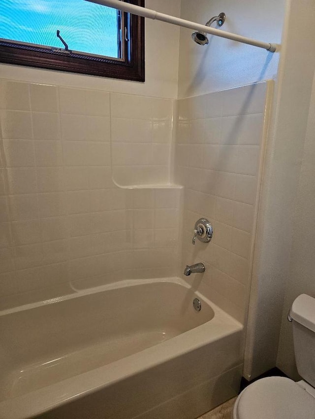 bathroom with toilet and tiled shower / bath