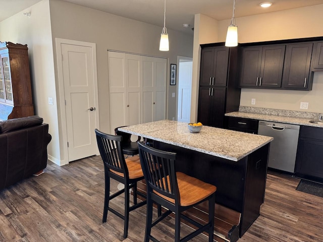 kitchen with decorative light fixtures, a center island, stainless steel dishwasher, dark hardwood / wood-style floors, and a breakfast bar