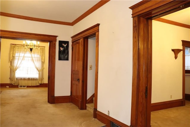 hall with light carpet, crown molding, and an inviting chandelier