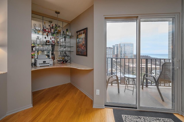 bar featuring wood-type flooring, a water view, hanging light fixtures, and lofted ceiling