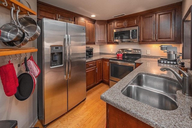 kitchen featuring stainless steel appliances, light hardwood / wood-style floors, and sink