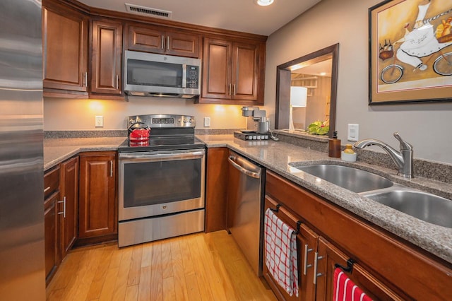 kitchen with appliances with stainless steel finishes, light wood-type flooring, and sink