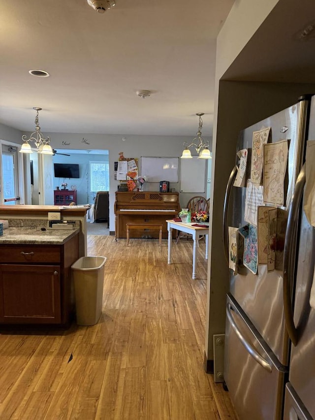 kitchen with decorative light fixtures, stainless steel fridge, light hardwood / wood-style floors, and an inviting chandelier