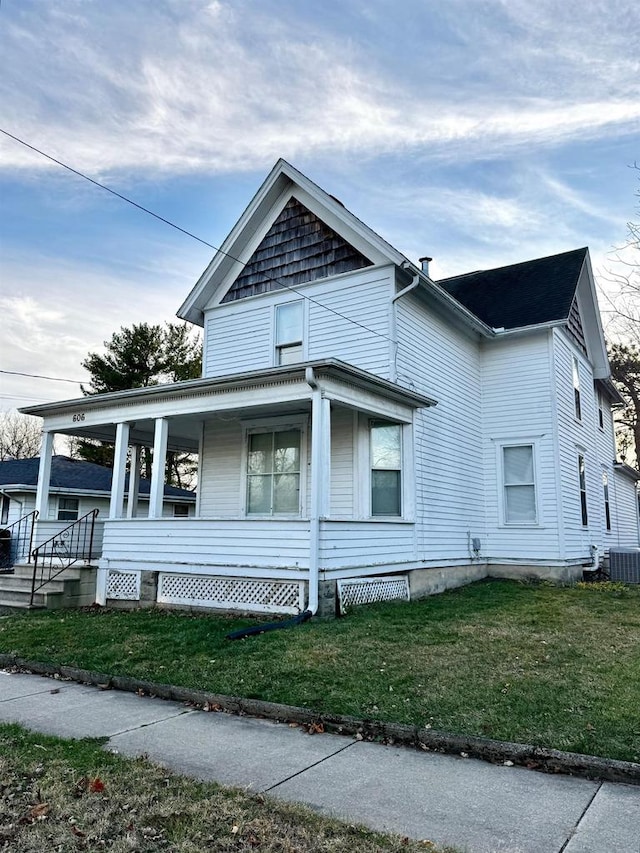 view of side of property featuring a lawn, a porch, and cooling unit