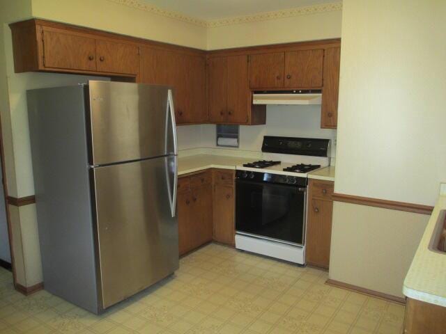 kitchen with white range with gas cooktop and stainless steel refrigerator