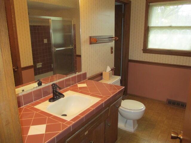 bathroom featuring vanity, toilet, and a shower with door