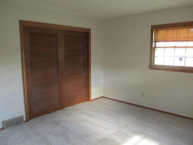 unfurnished bedroom featuring light carpet and a closet