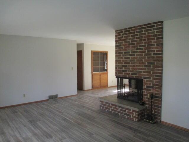 unfurnished living room with hardwood / wood-style flooring and a brick fireplace