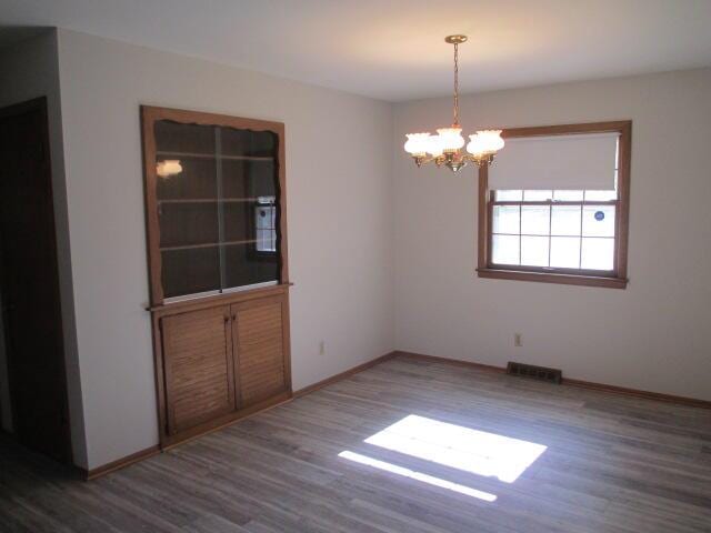 unfurnished room with hardwood / wood-style floors and a notable chandelier