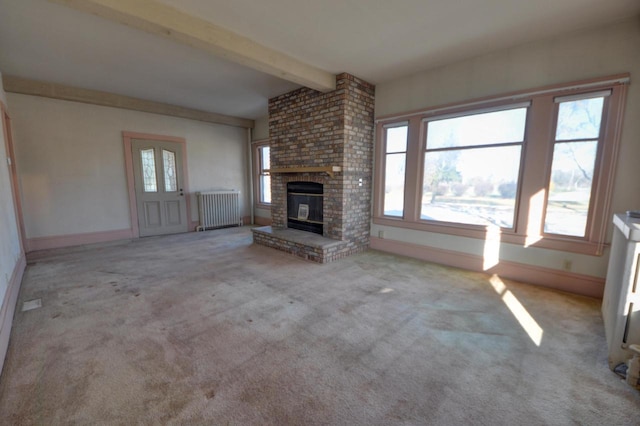 unfurnished living room with plenty of natural light, a fireplace, radiator, and light carpet