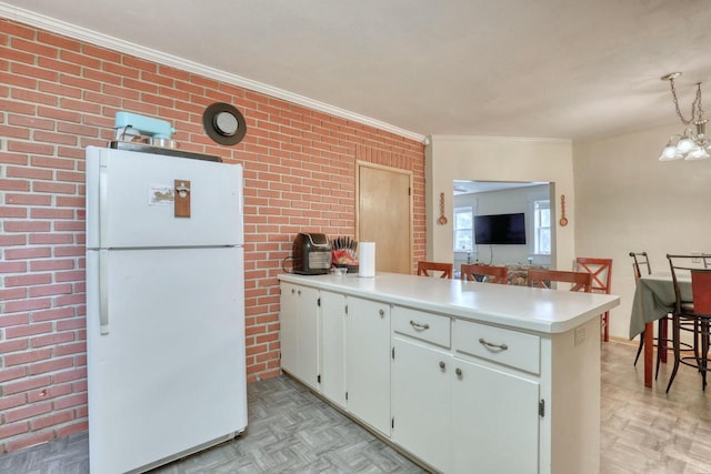 kitchen with an inviting chandelier, kitchen peninsula, white fridge, light parquet floors, and white cabinets