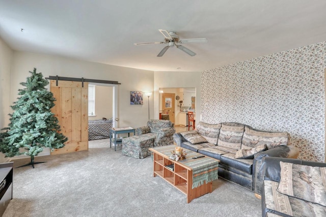 living room with a barn door, ceiling fan, and carpet