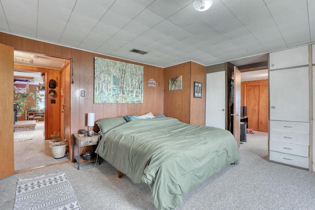 bedroom with light carpet, multiple windows, and wooden walls