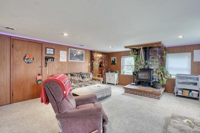 living room with carpet, a wood stove, and wood walls