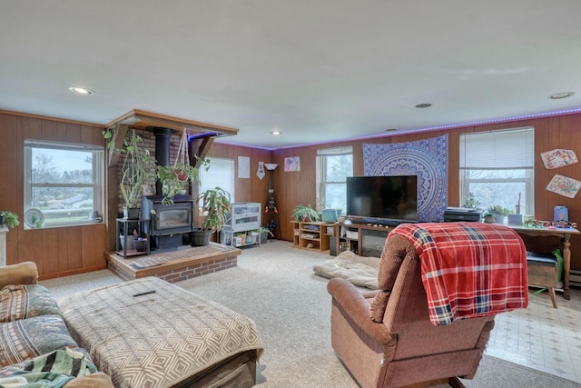 carpeted living room featuring plenty of natural light, a wood stove, and wooden walls