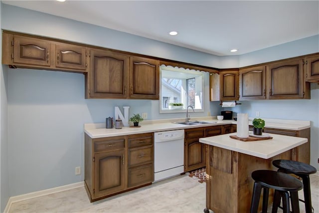 kitchen with white dishwasher, a breakfast bar, and sink