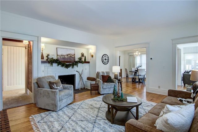 living room with hardwood / wood-style floors, an inviting chandelier, and a brick fireplace