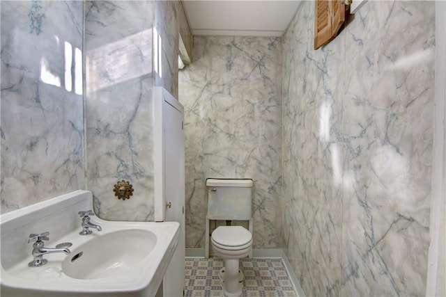 bathroom featuring toilet, sink, and tile walls