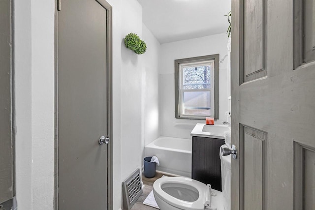 bathroom with a tub, vanity, and toilet