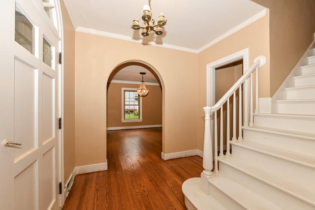 entrance foyer featuring hardwood / wood-style flooring, an inviting chandelier, and ornamental molding