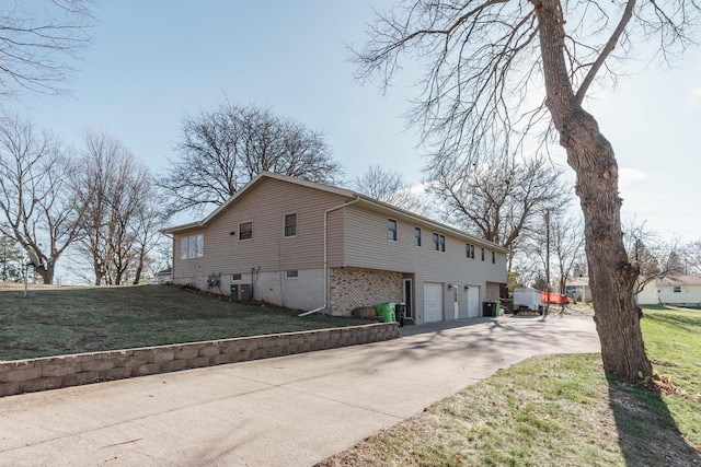 view of side of home featuring central air condition unit, a yard, and a garage