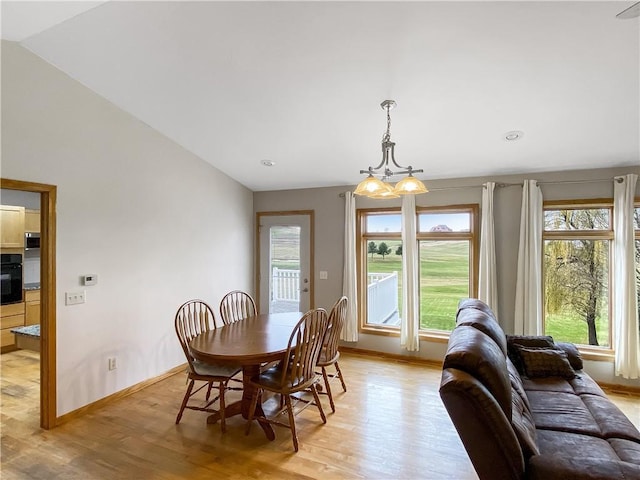 dining room featuring a chandelier, lofted ceiling, and light hardwood / wood-style flooring